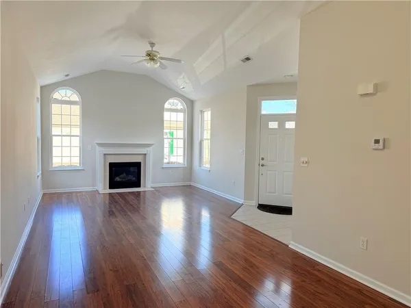an empty room with wooden floor a fireplace and windows