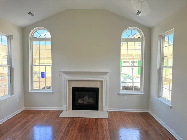 an empty room with wooden floor windows and a fireplace
