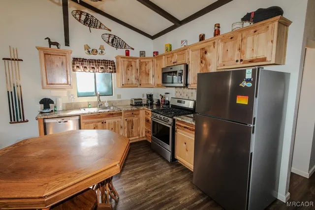 a kitchen with stainless steel appliances granite countertop a refrigerator a sink dishwasher a stove and white countertops with wooden floor