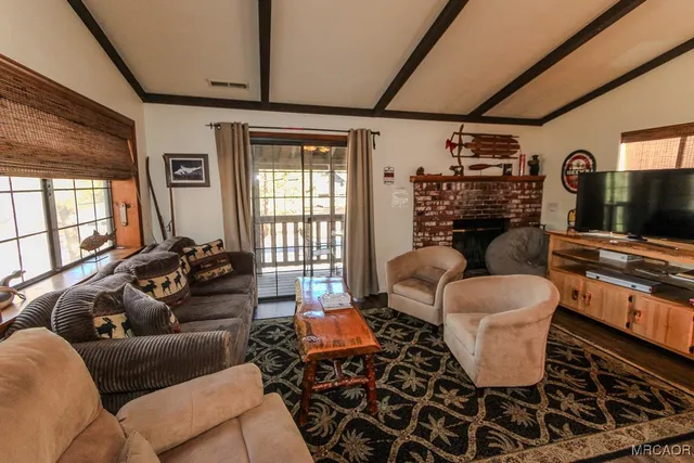 a living room with furniture a flat screen tv and floor to ceiling window