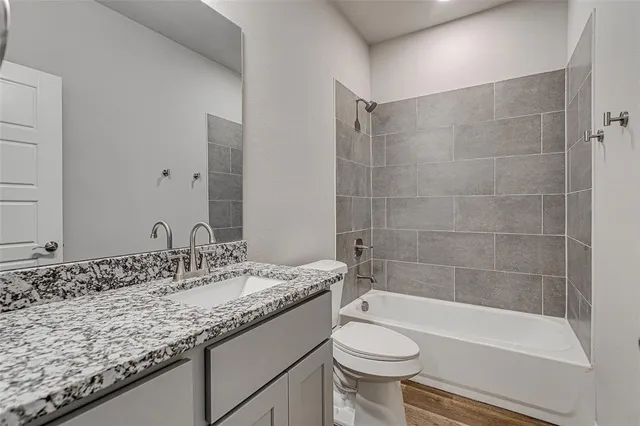 a bathroom with a granite countertop sink a toilet a mirror and bathtub