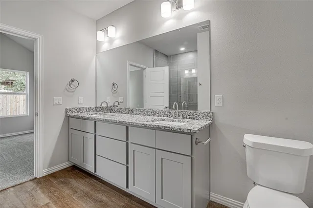 a bathroom with a granite countertop toilet sink and mirror