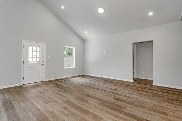 a view of an empty room with wooden floor and windows