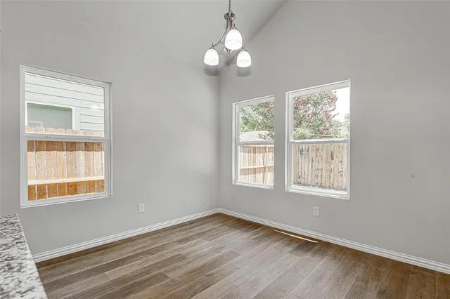 an empty room with wooden floor cabinet and windows