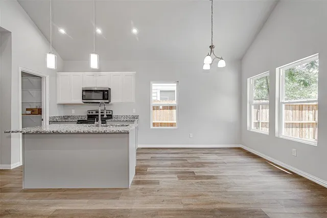 a view of a kitchen with granite countertop stainless steel appliances cabinets a sink and a counter top space