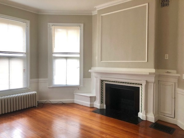 an empty room with wooden floor a fireplace and windows