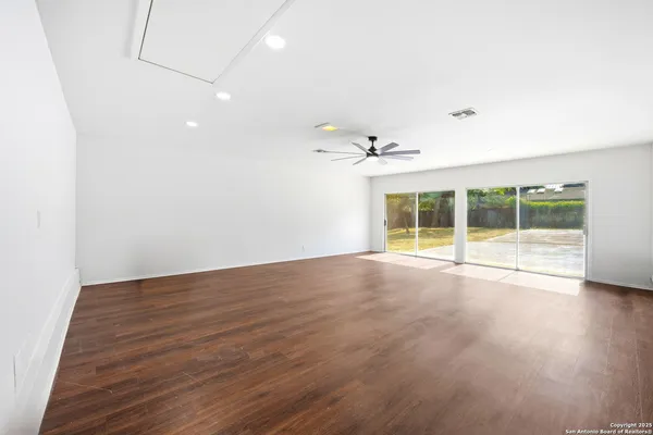 an empty room with wooden floor and fan
