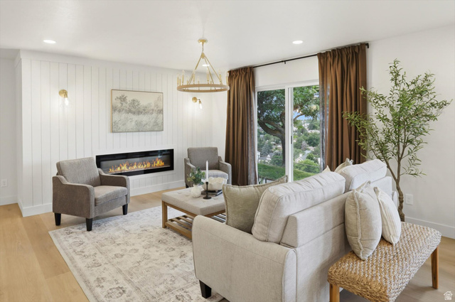 8760 Rustler Road Cottonwood Heights, UT 84093 - Photo 9 of 57 Living area featuring a modern fireplace inset into a shiplap accent wall, light wood-finish flooring, a contemporary chandelier, and recessed lighting