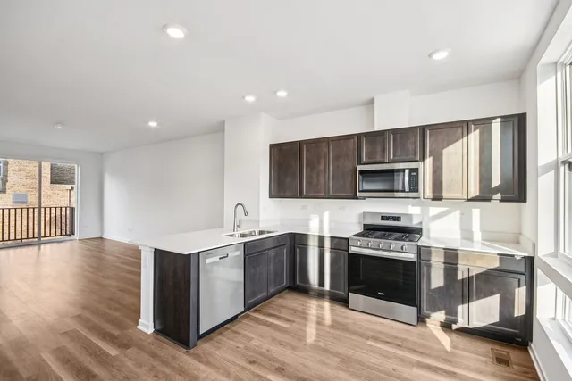 a kitchen with stainless steel appliances granite countertop a stove top oven a sink and a refrigerator