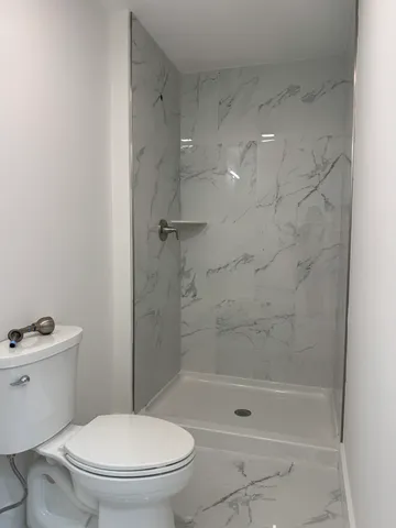 a white toilet sitting next to a bath tub