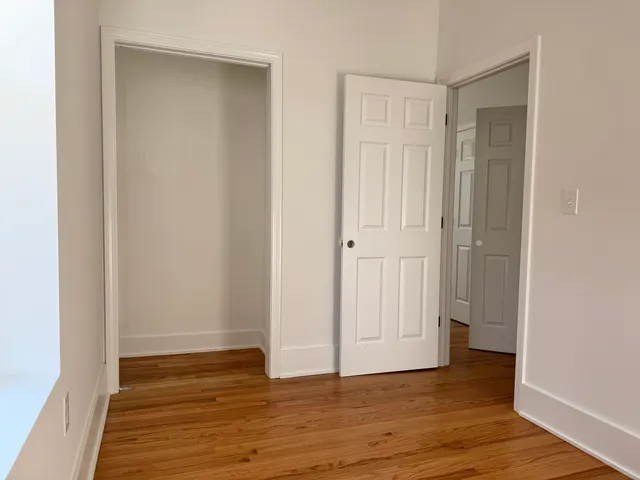 a view of an empty room with wooden floor and closet