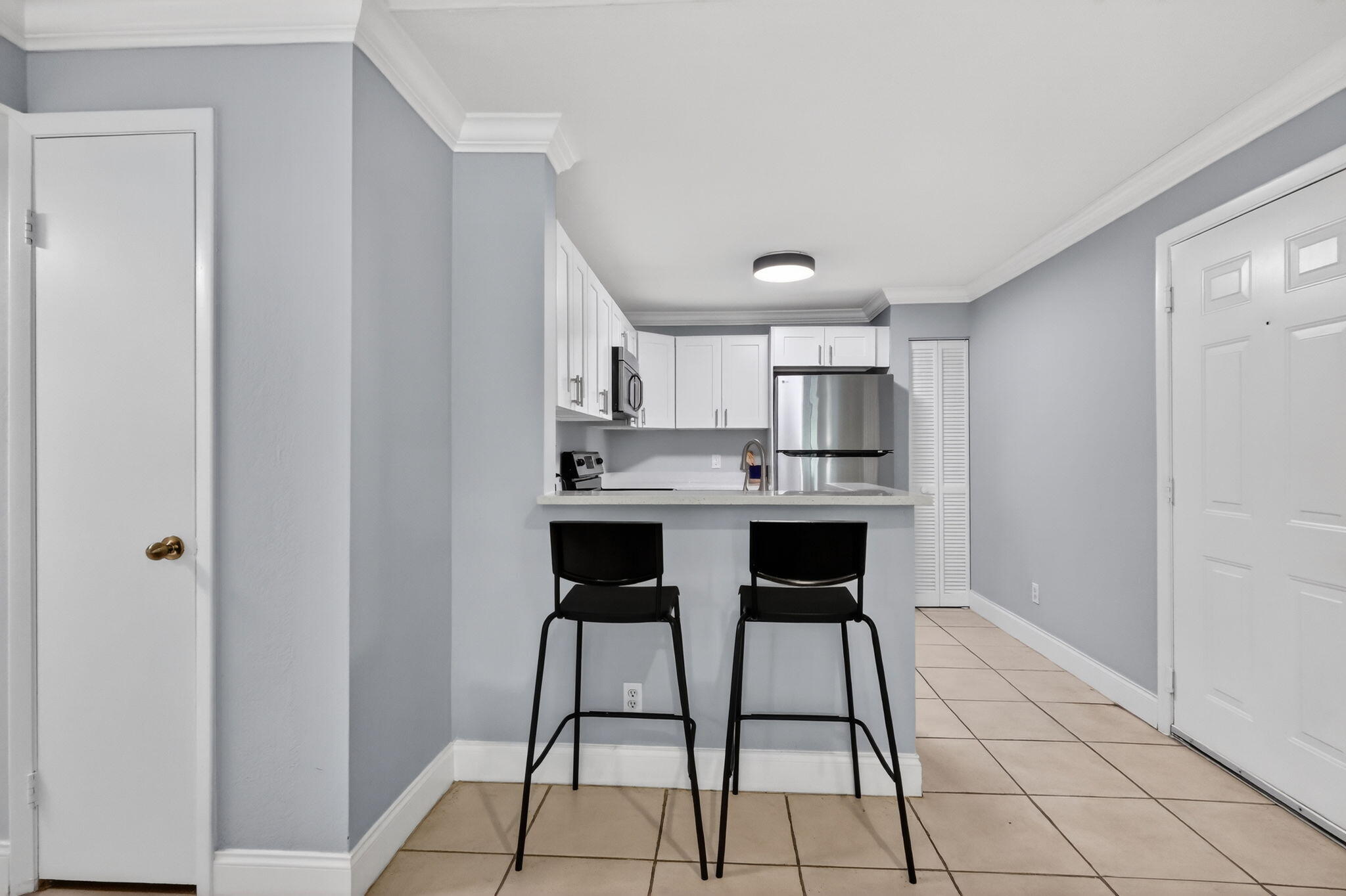 1740 Palm Cove Boulevard, Unit 4307 Delray Beach, FL 33445 - Photo 3 of 31 a kitchen with stainless steel appliances kitchen island a table chairs in it and white cabinets