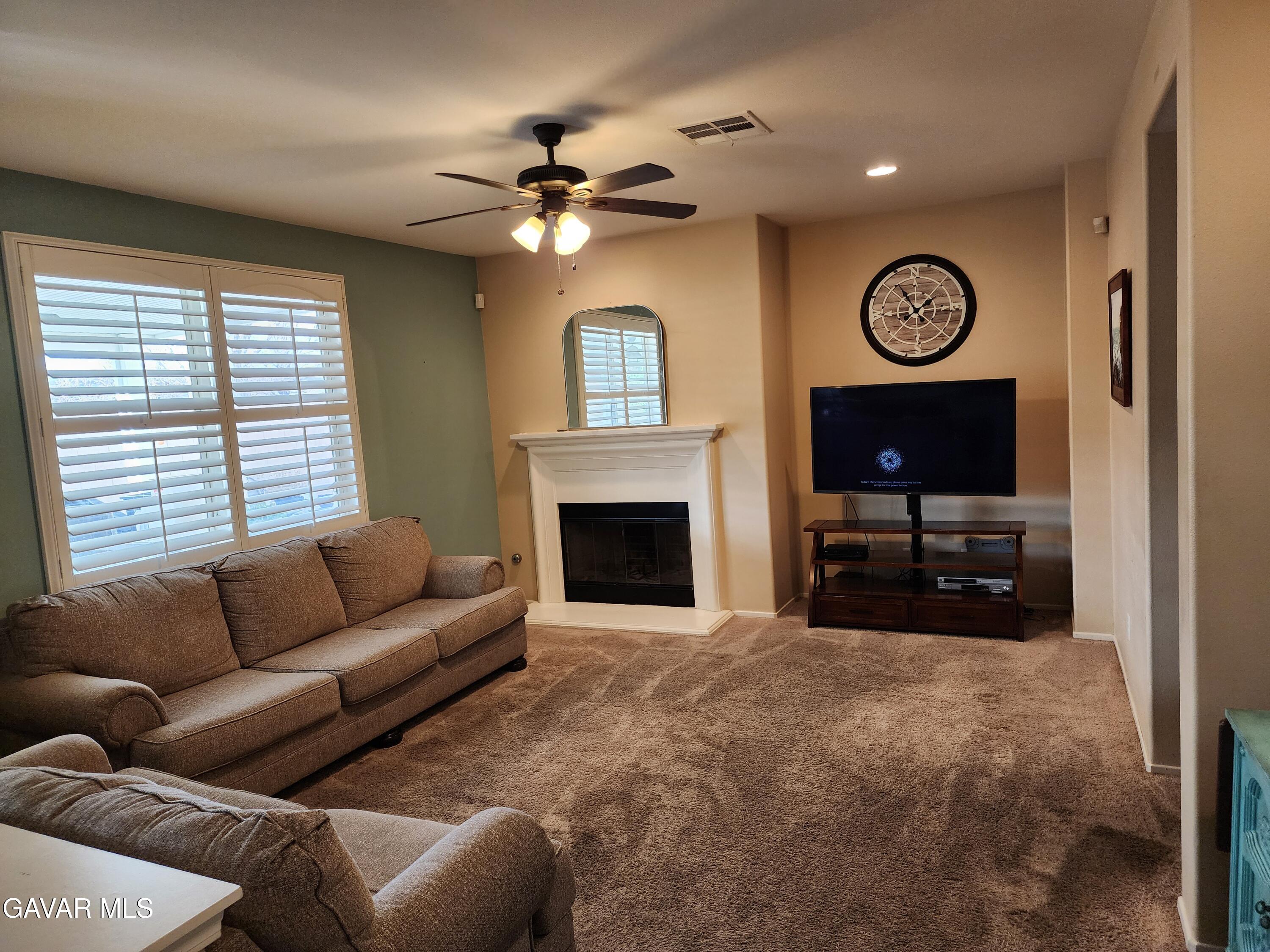 44741 Ruthron Avenue Lancaster, CA 93536 - Photo 3 of 13 a living room with furniture a clock and a window