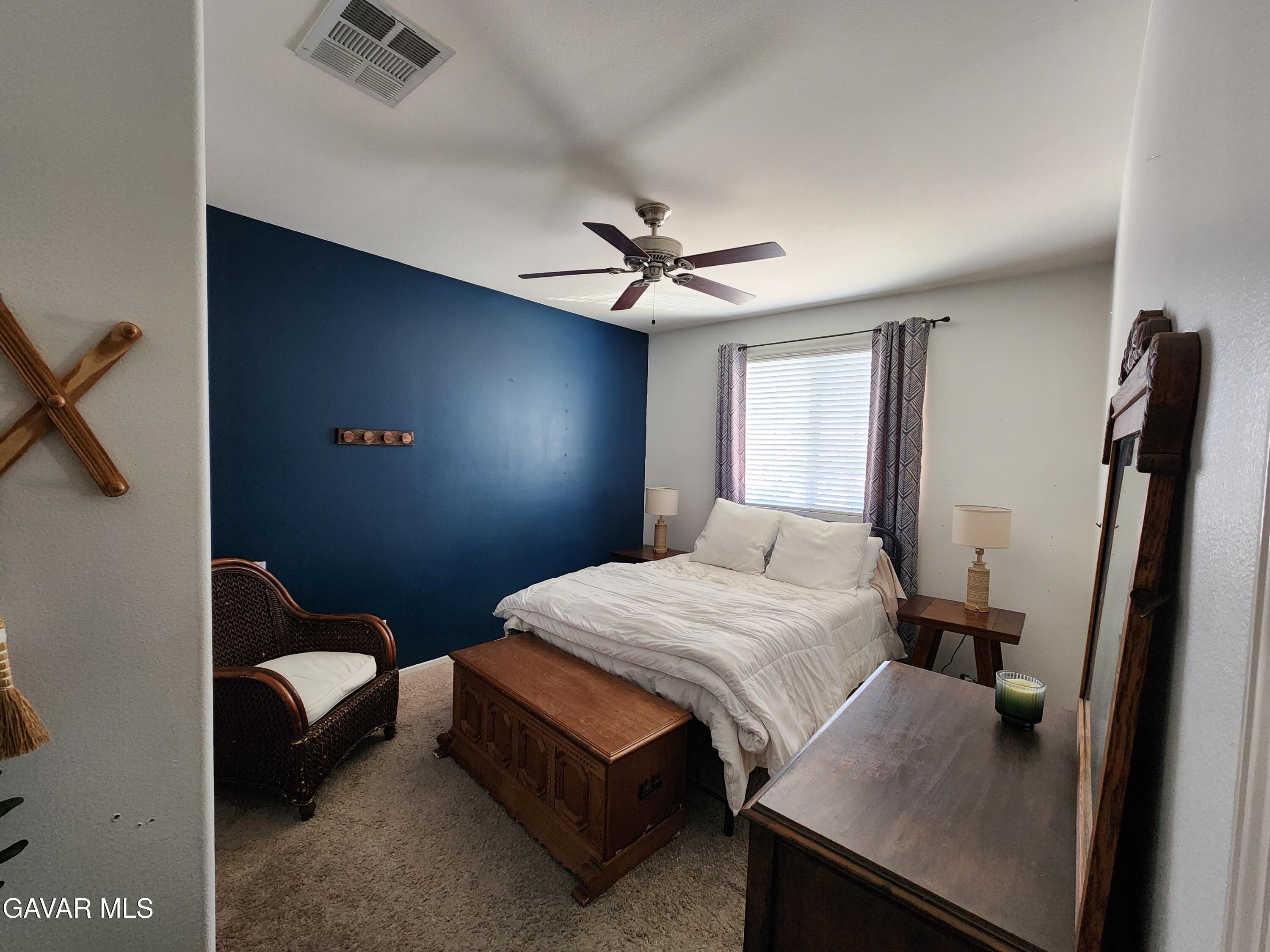 44741 Ruthron Avenue Lancaster, CA 93536 - Photo 5 of 13 a bedroom with a bed and a chandelier