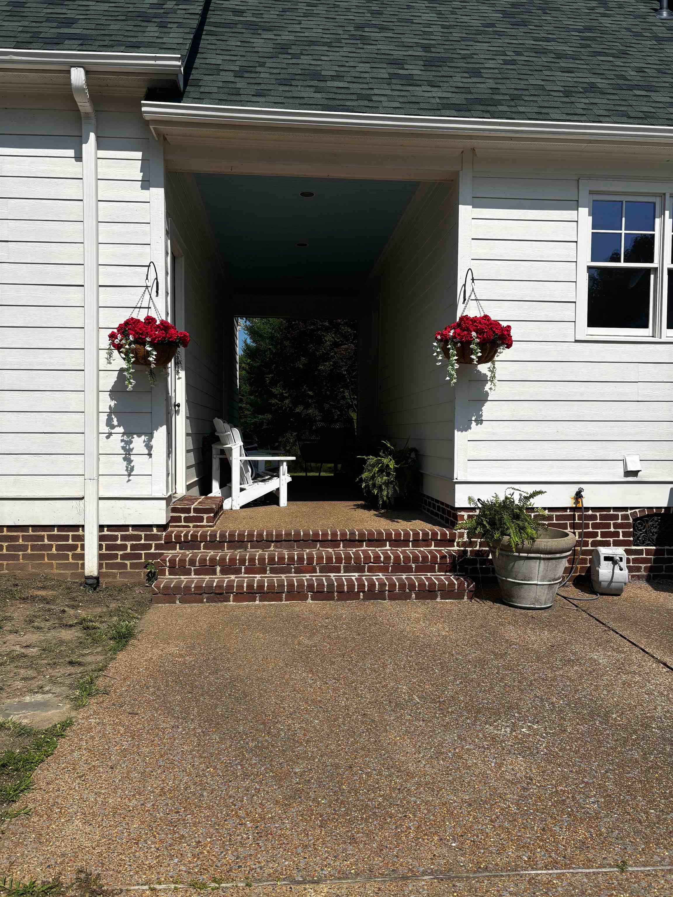 1915 Teague Store Road Somerville, TN 38068 - Photo 14 of 38 Covered walkway featuring white siding, a dark green shingle roof, brick steps, and exposed aggregate concrete paving
