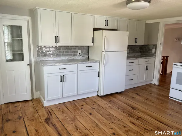 a kitchen with granite countertop a refrigerator sink and cabinets