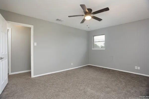 an empty room with a window and a fan