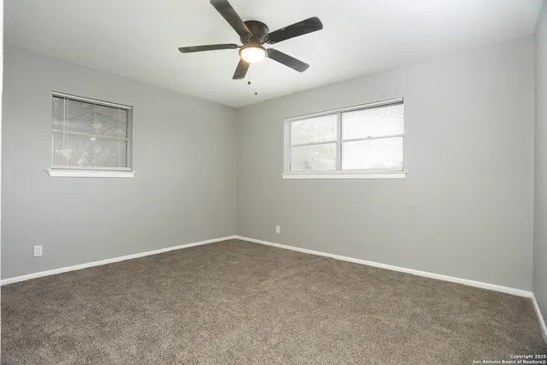 en empty room with ceiling fan and window