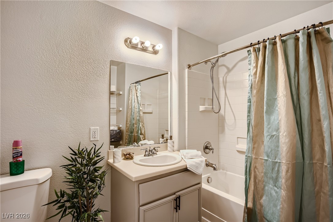 7701 West Robindale Road, Unit 149 Las Vegas, NV 89113 - Photo 18 of 22 Bathroom with a textured wall, shower / bath combo with shower curtain, and vanity