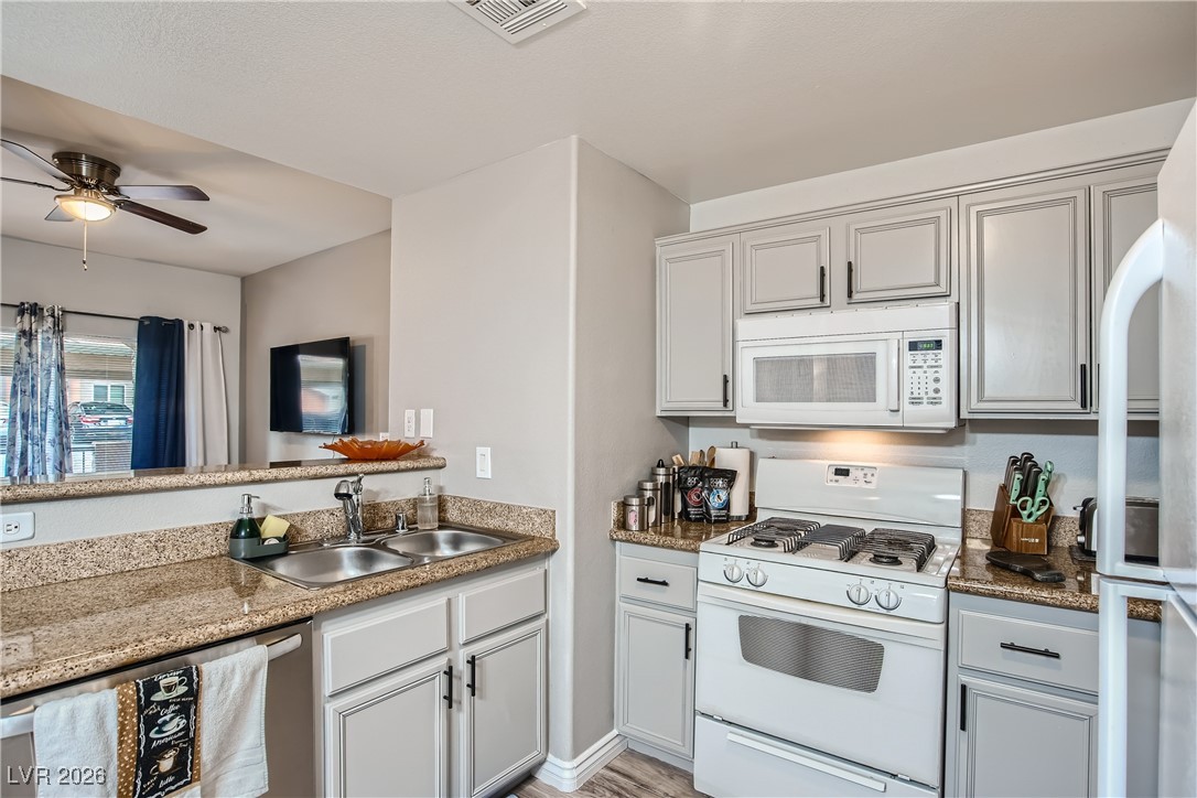 7701 West Robindale Road, Unit 149 Las Vegas, NV 89113 - Photo 7 of 22 Kitchen featuring white appliances, dark stone counters, and ceiling fan