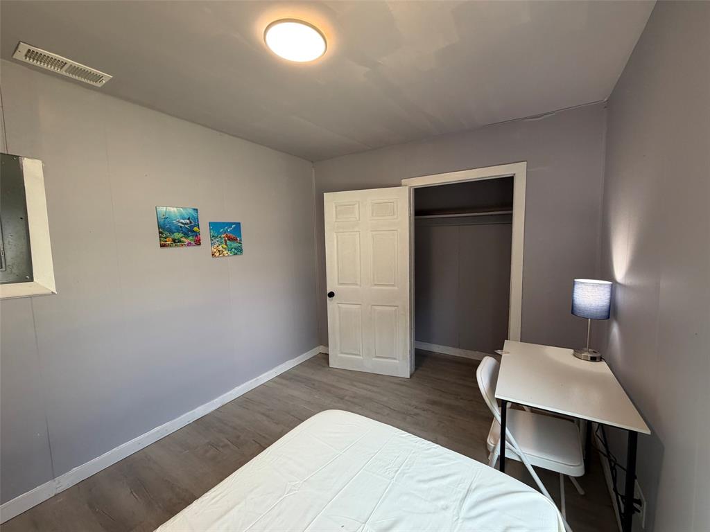 513 Shawnee Trace Grand Prairie, TX 75051 - Photo 16 of 32 Bedroom featuring wood-finish flooring, light gray wall paint, and a built-in closet with bi-fold doors