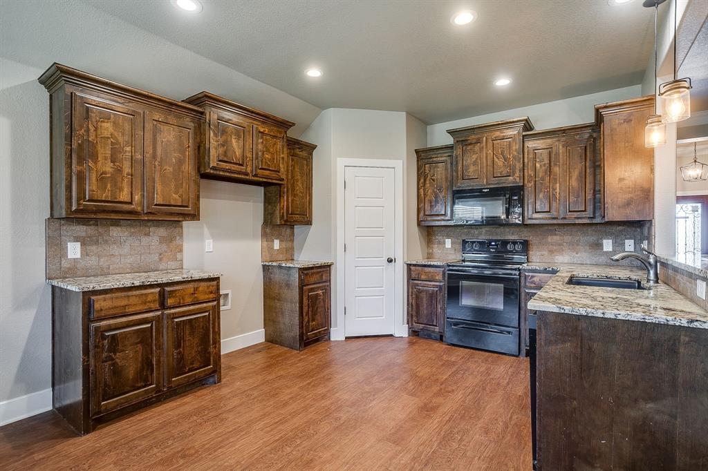 110 Hummingbird Drive Weatherford, TX 76085 - Photo 12 of 38 a kitchen with stainless steel appliances granite countertop a stove top oven a sink dishwasher a refrigerator and a microwave oven with wooden floor