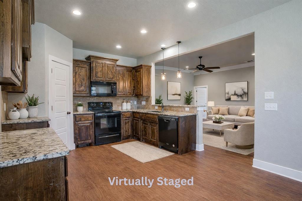 110 Hummingbird Drive Weatherford, TX 76085 - Photo 15 of 38 a kitchen with kitchen island granite countertop a stove top oven a sink dishwasher a refrigerator and a dining table with wooden floor