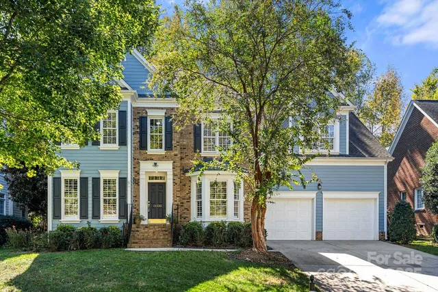 a front view of a house with a yard and trees