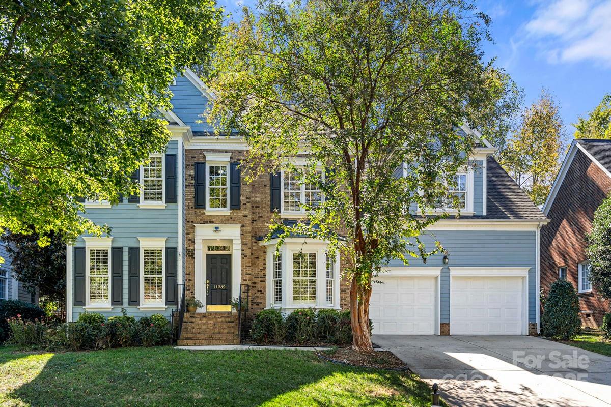 a front view of a house with a yard and trees