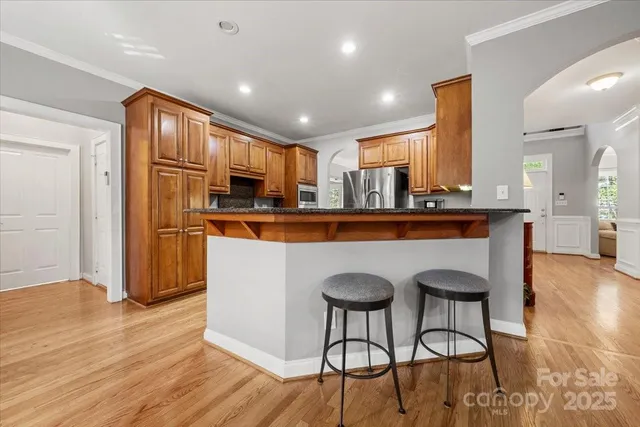 a kitchen with stainless steel appliances granite countertop a refrigerator a stove top oven and a dining table with wooden floor