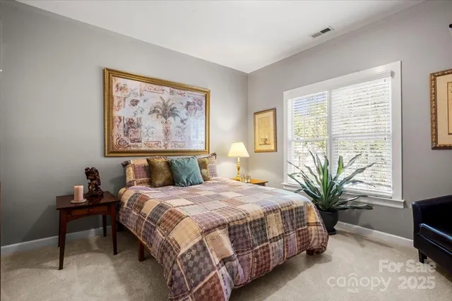 a bedroom with a bed a couch and potted plant on the dresser