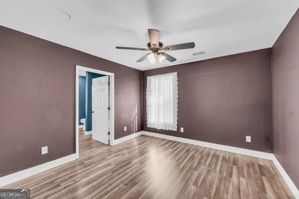 a view of an empty room with window and wooden floor