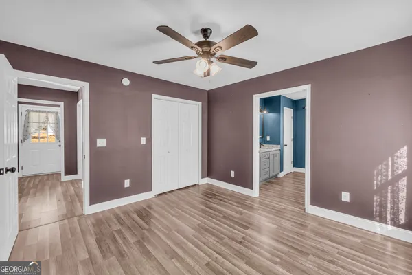 a view of an empty room with wooden floor and a ceiling fan