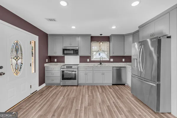 a kitchen with a refrigerator a sink and dishwasher with wooden floor