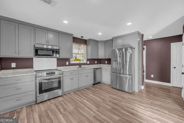 a kitchen with a refrigerator a stove top oven a sink and dishwasher with wooden floor