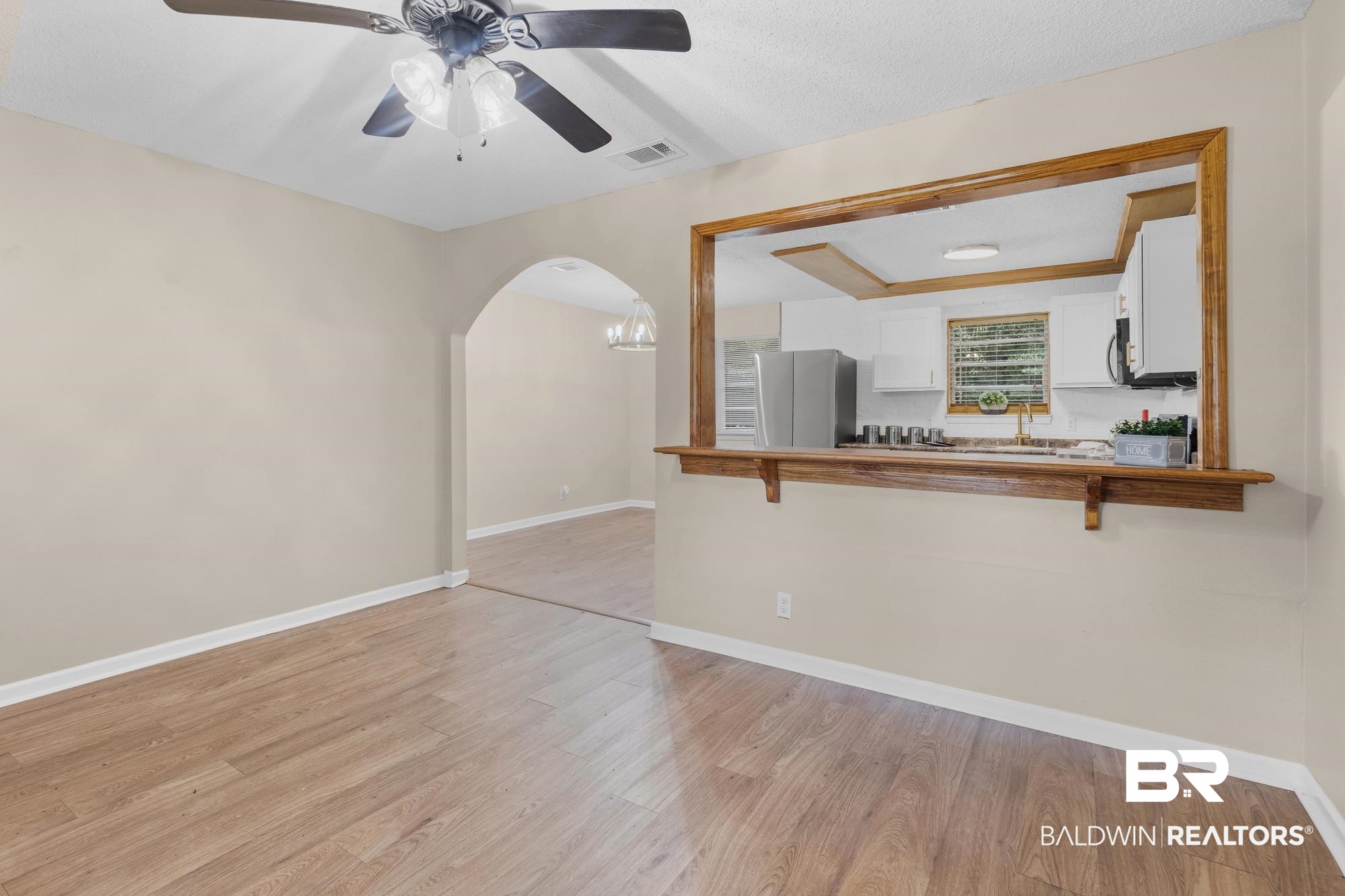 1560 Military Road Mount Vernon, AL 36560 - Photo 11 of 26 Open concept interior featuring wood-finish flooring, a ceiling fan with integrated lighting, and a pass-through window with a wood trim and bar counter