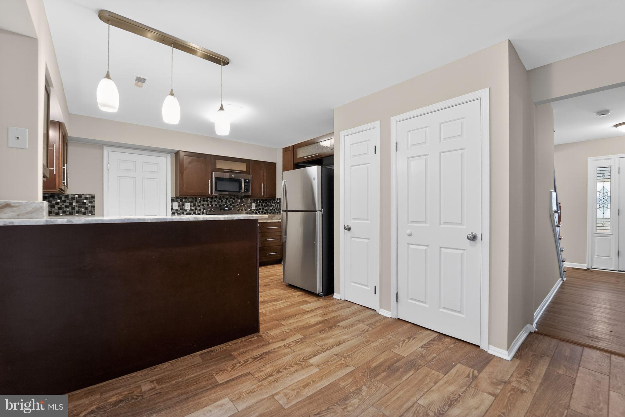 5904 Mardella Boulevard Clinton, MD 20735 - Photo 19 of 34 a kitchen with stainless steel appliances granite countertop a refrigerator a sink a stove a microwave and wooden floors