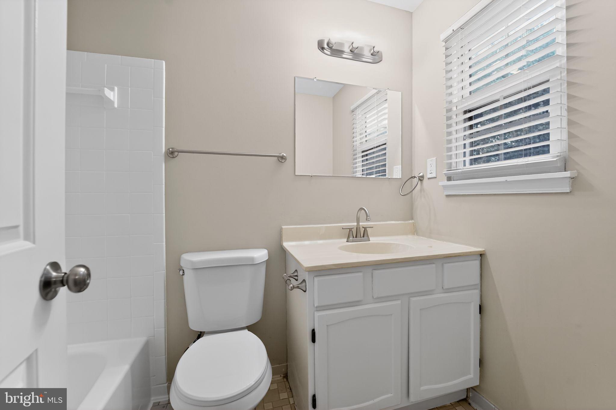 5904 Mardella Boulevard Clinton, MD 20735 - Photo 23 of 34 a bathroom with a toilet a sink a mirror and a window