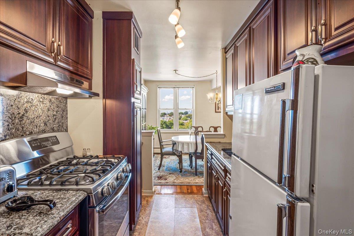 151-05 Cross Island Parkway, Unit 6C Queens, NY 11357 - Photo 13 of 20 a kitchen with stainless steel appliances granite countertop a stove a refrigerator and a wooden cabinets