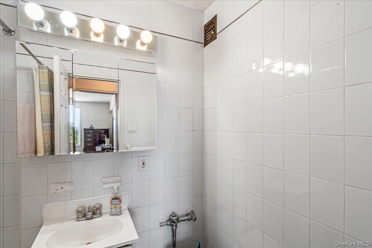 151-05 Cross Island Parkway, Unit 6C Queens, NY 11357 - Photo 14 of 20 a bathroom with a sink mirror and toilet