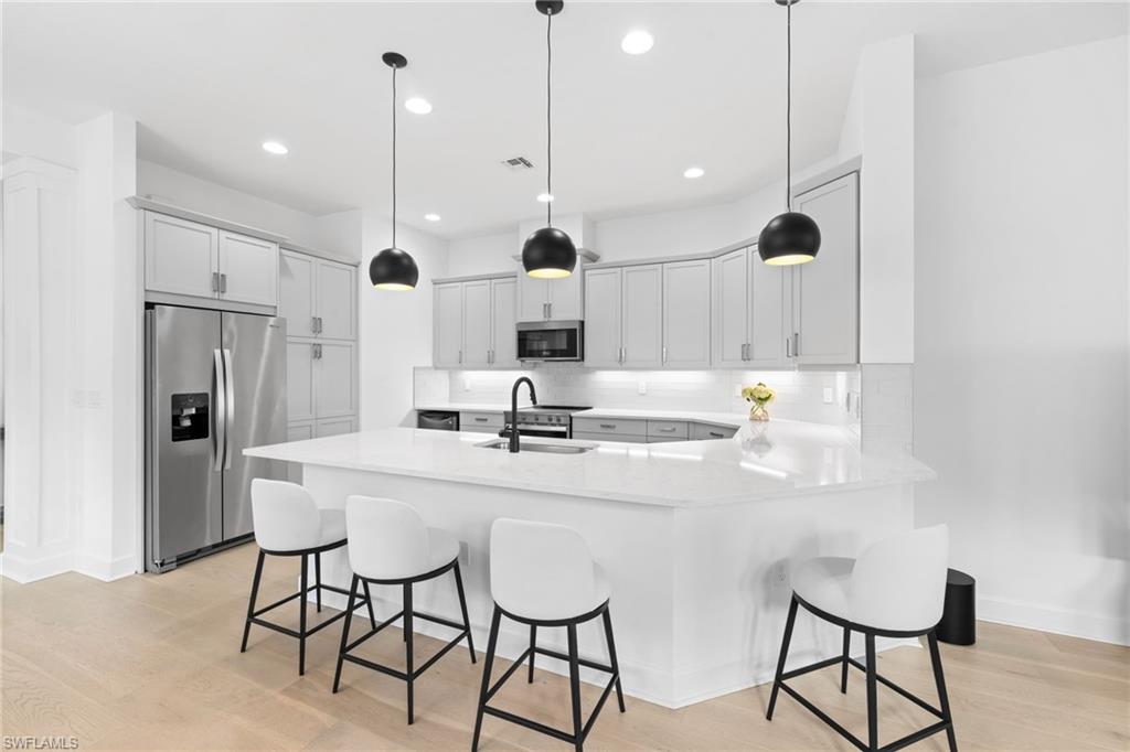 6291 Arriba Avenue Naples, FL 34113 - Photo 10 of 43 a kitchen with stainless steel appliances kitchen island granite countertop a sink and chairs