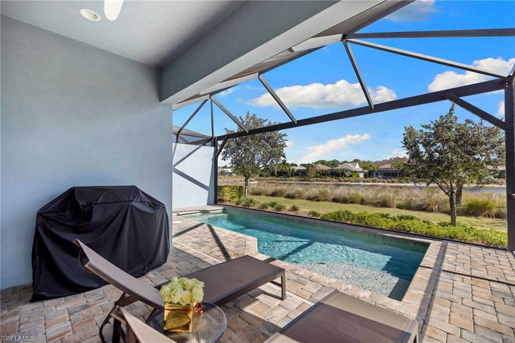 6291 Arriba Avenue Naples, FL 34113 - Photo 19 of 43 a living room with a couch and a floor to ceiling window