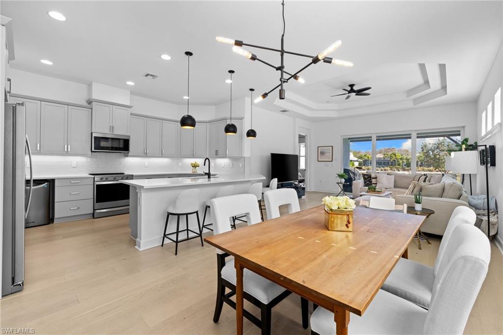 6291 Arriba Avenue Naples, FL 34113 - Photo 6 of 43 a dining room with stainless steel appliances kitchen island granite countertop a dining table chairs and a refrigerator