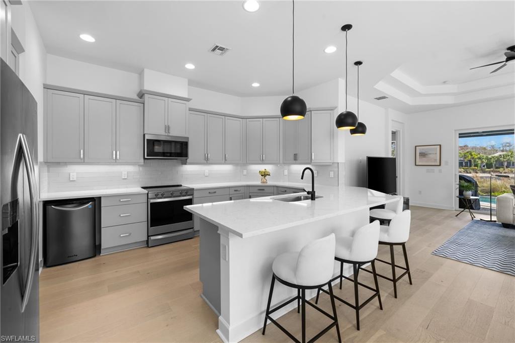 6291 Arriba Avenue Naples, FL 34113 - Photo 8 of 43 a kitchen with stainless steel appliances kitchen island granite countertop a stove a sink a microwave a island with a dining table and chairs