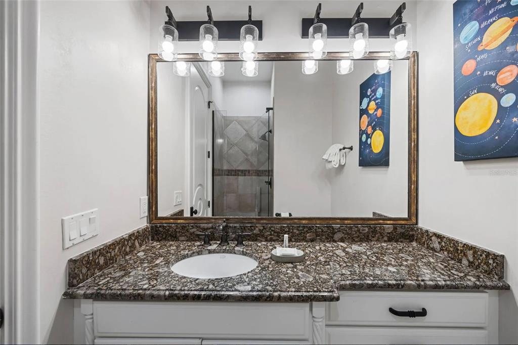 304 Muirfield Loop Reunion, FL 34747 - Photo 34 of 85 a bathroom with a granite countertop sink and a mirror