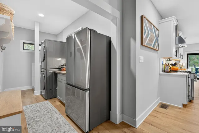 a white house with a big yard and large trees with wooden fence