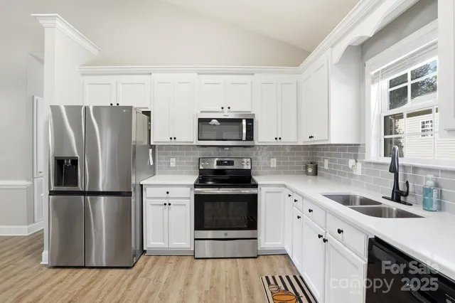 a kitchen with cabinets stainless steel appliances a sink a stove and a window