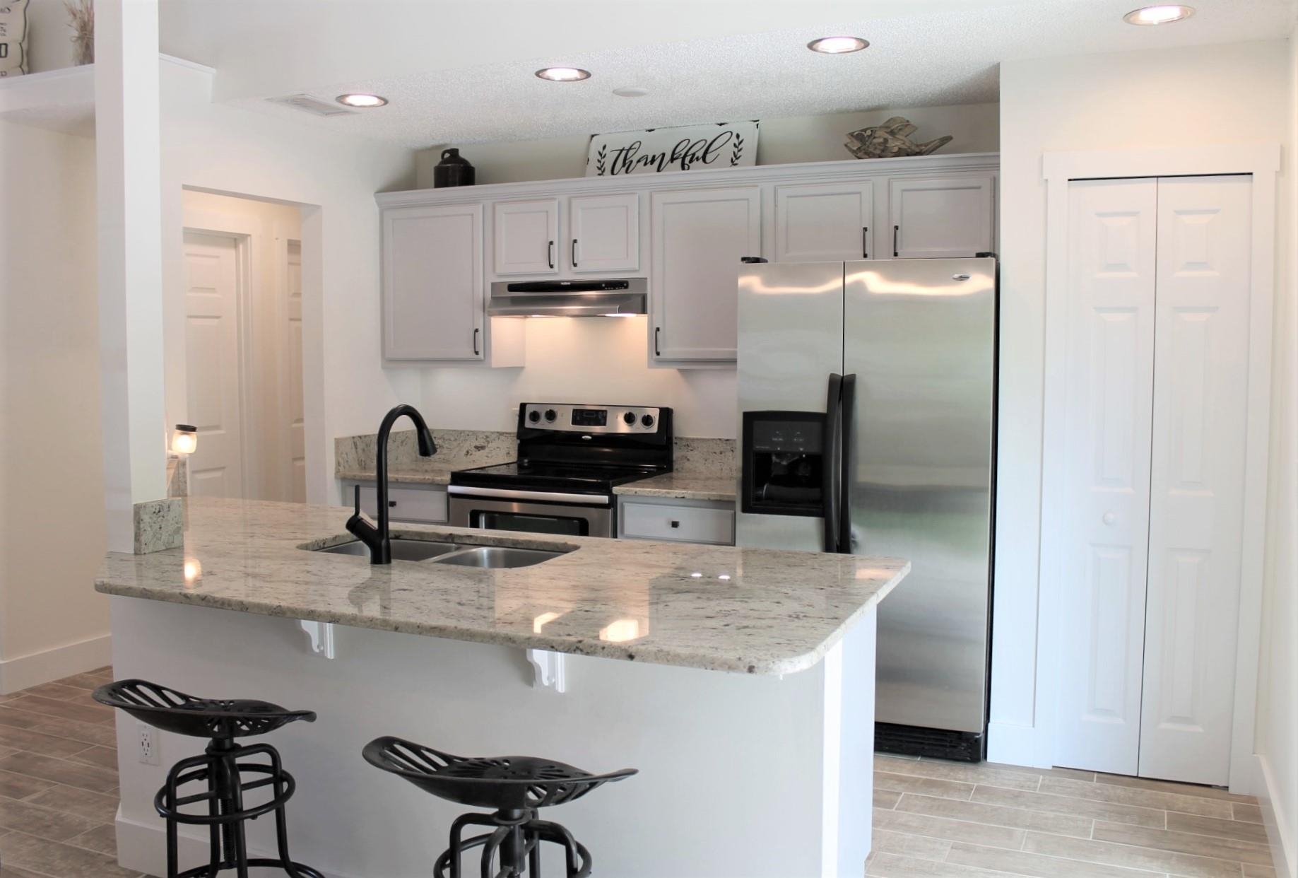 215 Yale Road St. Augustine, FL 32086 - Photo 12 of 35 a kitchen with stainless steel appliances a refrigerator a stove a sink and chairs