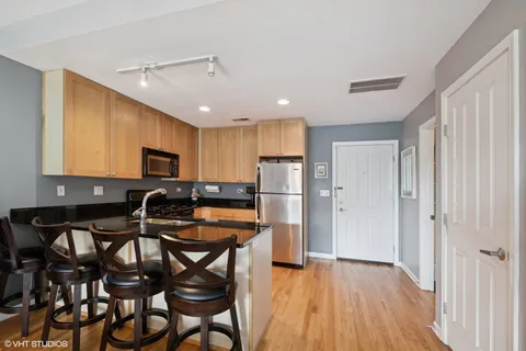 a kitchen with stainless steel appliances a table chairs refrigerator and microwave