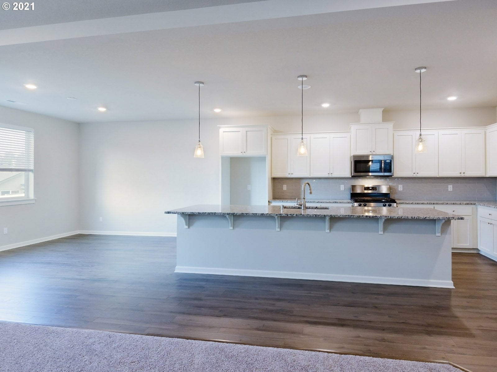3733 South 42nd Place Ridgefield, WA 98642 - Photo 5 of 23 a kitchen with granite countertop a stove a sink a refrigerator and white cabinets with wooden floor